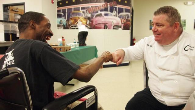 Charles Mortimer gives a fist bump to a man in a wheelchair. 