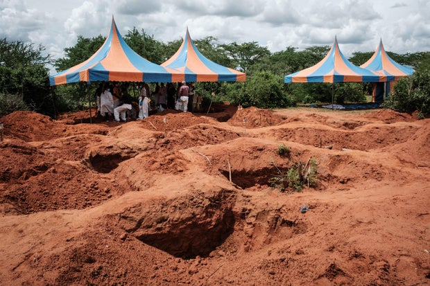 Workers take shelter while digging to exhume bodies from the mass-grave site in Shakahola, Kenya, outside the coastal town of Malindi, April 25, 2023