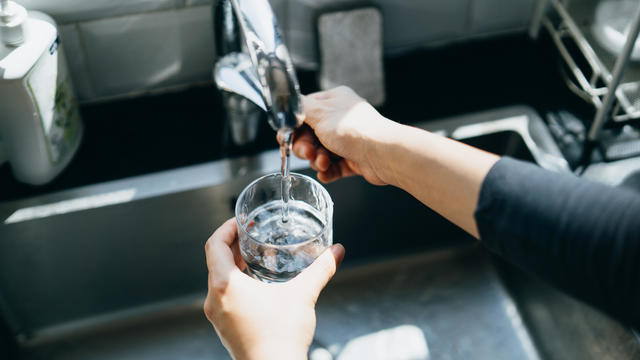 Cropped shot of woman's hand filling a glass of filtered water right from the tap in the kitchen sink at home 