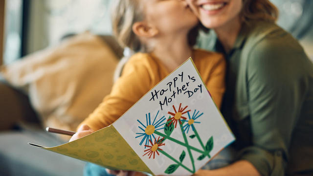 woman receiving Mother's day greeting card from her daughter 