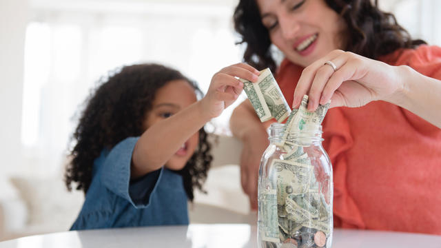 Mother and daughter saving money in jar 