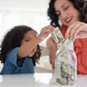 Mother and daughter saving money in jar 