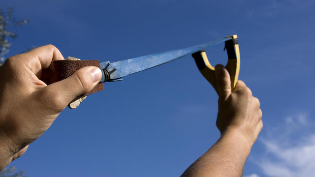 A rock is pulled back in an sling shot pointed to the sky 