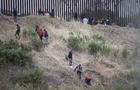 Asylum seekers are seen scaling a hill between the US-Mexico 