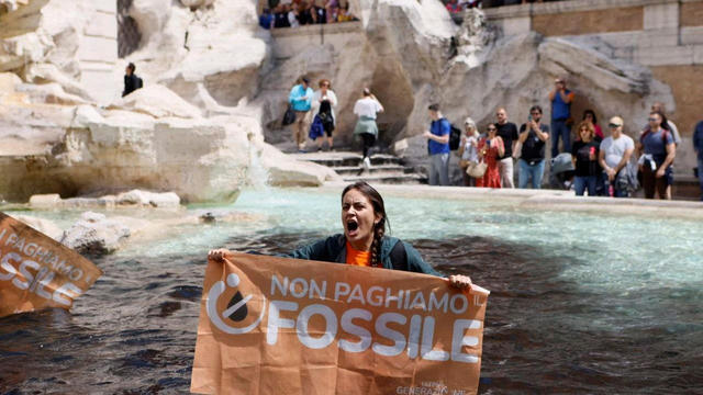 Climate activist holds banner in Trevi Fountain, Rome 