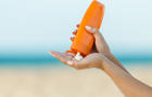 Woman hand apply sunscreen on the beach 