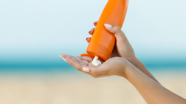 Woman hand apply sunscreen on the beach 
