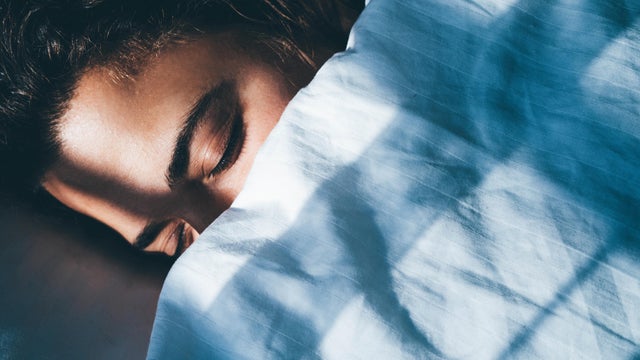 Lady sleeps in bed tossing turning in dream under blanket