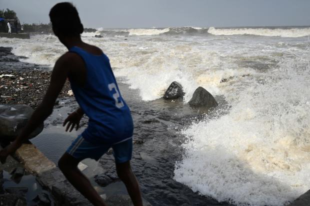 A boy moves away from the seafront as high waves hit the coast in Mumbai, India, June 13, 2023, as Cyclone Biparjoy makes its way across the Arabian Sea toward the coastlines of India and Pakistan. 