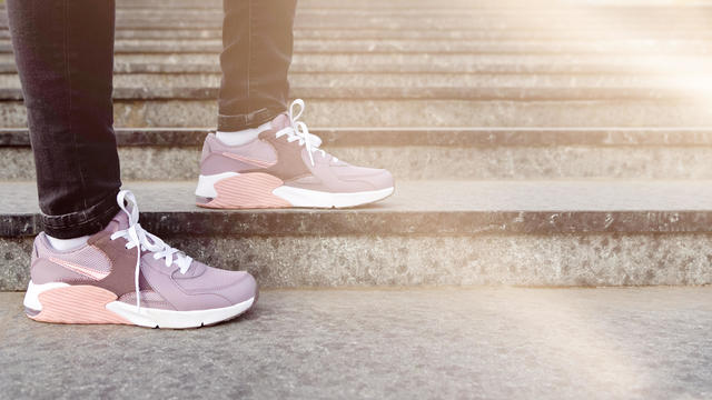cropped image of woman standing on steps in purple and pink shoes 