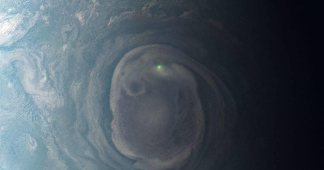 A NASA spacecraft captures a glowing green blob on Jupiter caused by a lightning bolt