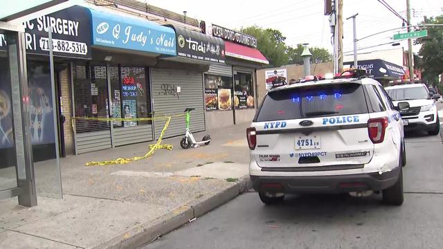 An NYPD vehicles sits parked outside a closed nail salon that is blocked off with crime scene tape. 