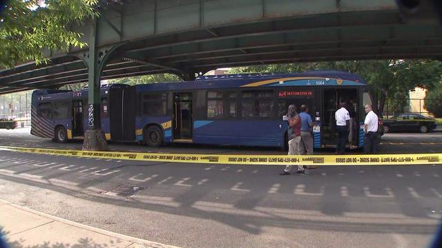An MTA bus parked on a street behind crime scene tape. 