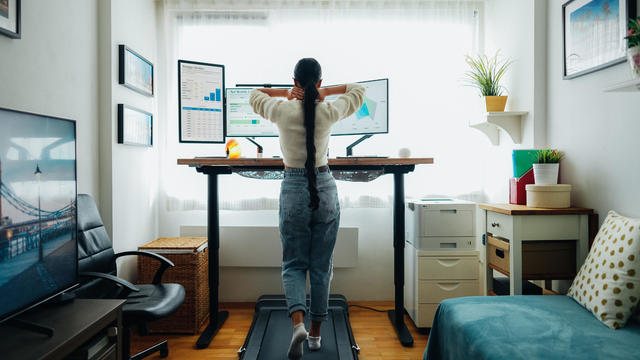 Person working at standing desk while walking on under-desk treadmill 