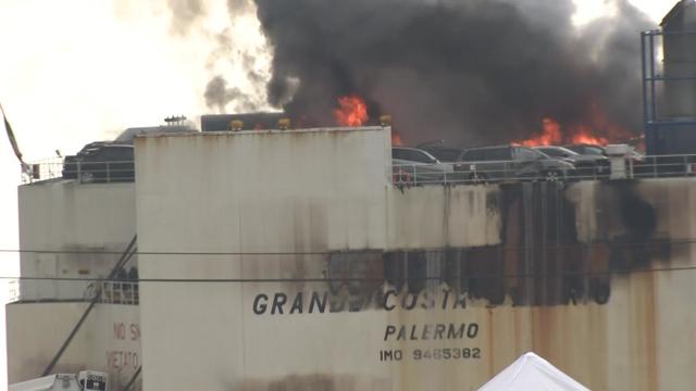 Flames and black smoke can be seen pouring from vehicles on board a cargo ship in Port Newark. 