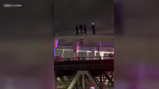 Two police officers and two juveniles walk down the top of the Manhattan Bridge. 
