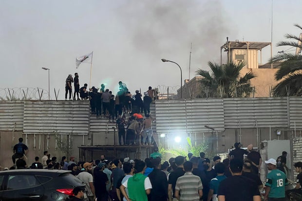 CORRECTS SECOND SENTENCE - Protesters scale a wall at the Swedish Embassy in Baghdad Thursday, July 20, 2023. Protesters angered by the planned burning of a copy of the Quran stormed the embassy early Thursday, breaking into the compound and lighting a small fire