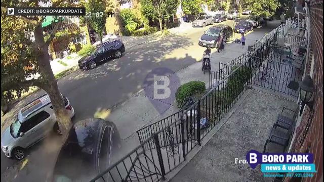 Surveillance video shows an SUV crashed into a building in Brooklyn as people stand on the sidewalk nearby. 