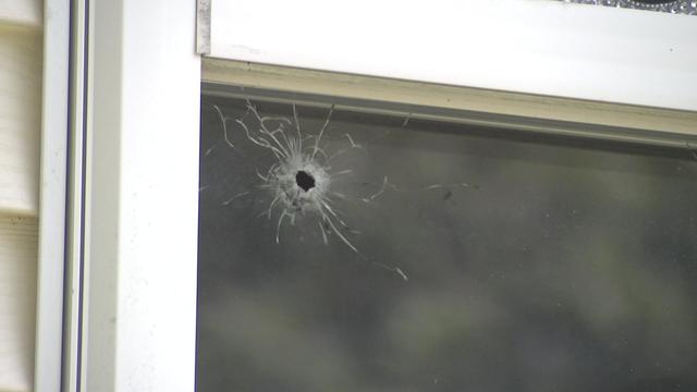 A bullet hole in the window of a home. 