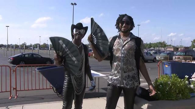 Two men wave black fans with the word "Renaissance" on them in silver. 