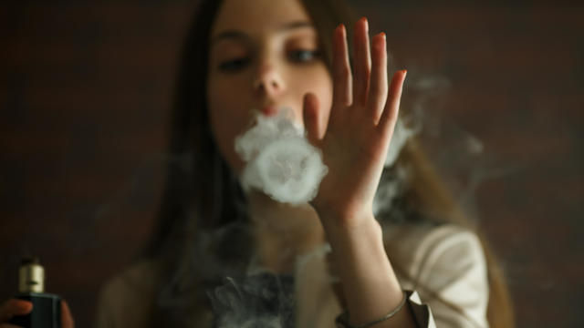 Vaping teenager. Young white girl smokes an electronic cigarette  in vape bar. Bad habit 