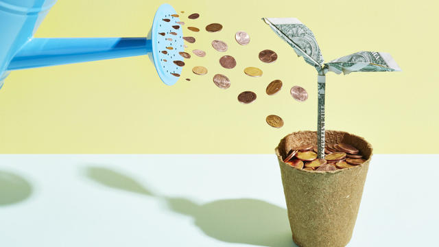 Origami dollar seedling being watered with coins 