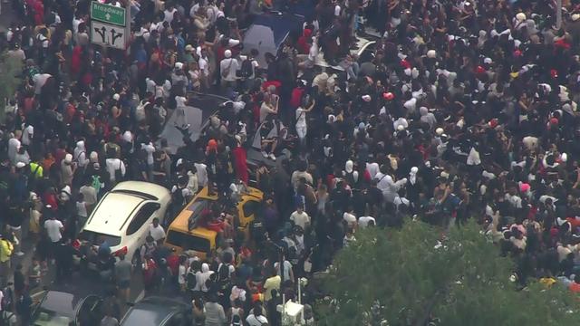 An aerial view of thousands of people crowded into Union Square. Multiple people stand on vehicles. 