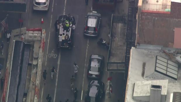 An aerial view of several people clinging onto the back and sides of an SUV as it leaves the Union Square area. 
