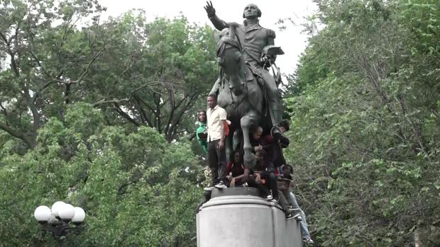 Multiple people stand on a statue in Union Square. 