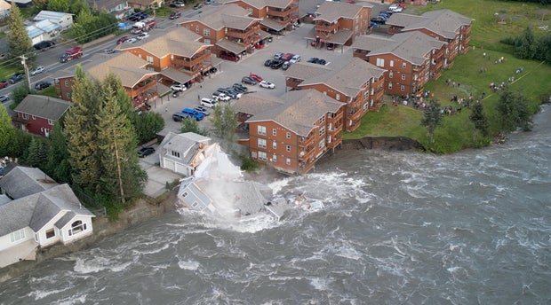 A drone view shows a house collapsing into a river due to glacial floods in Juneau
