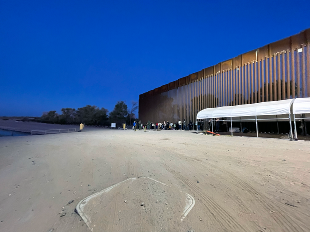 Families and adults from China, Colombia, Senegal and other countries wait to be transported by Border Patrol near Yuma, Arizona after crossing into the U.S. before sunrise.