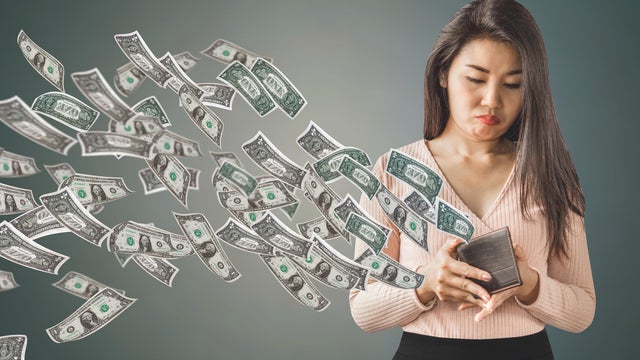poor Asian woman holding  purse having problem with money flying away, over spending concept 