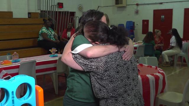 An incarcerated woman hugs her mom at carnival-themed family day inside a gymnasium. 