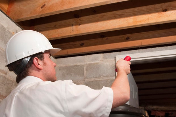 A pest control technician looks under a home for signs of termites or other pests.