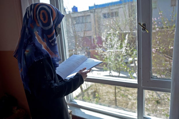 Deena Rahimi, a twelfth-grade student, reads a book at her residence in Kabul on March 21, 2023. Afghanistan's schools reopened in March, but hundreds of thousands of girls remain barred from attending class.