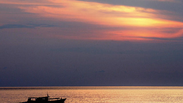 A fishing boat sails at dawn with their 