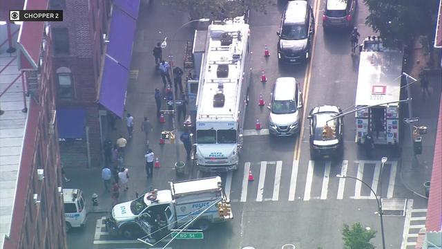 An aerial view of multiple NYPD vehicles and officers on a Queens street. 