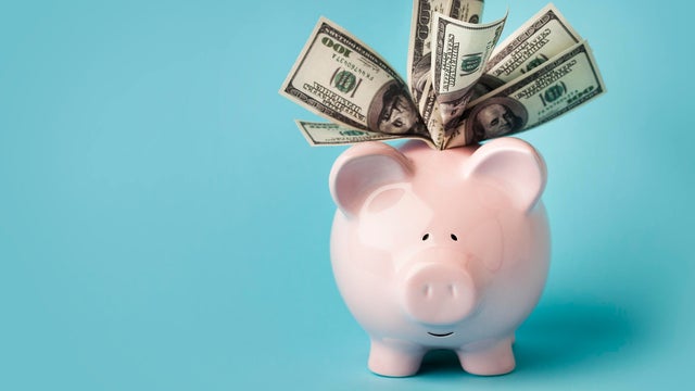 Pink piggybank stuffed with dollar bills 