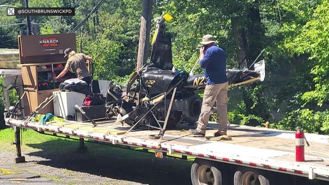 Partial helicopter wreckage on the back of a flatbed truck. 