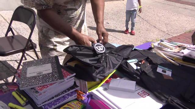 An individual fills a backpack with school supplies. 