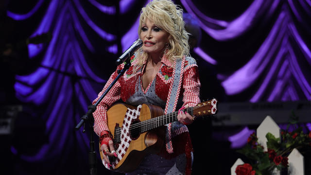 Dolly Parton performing with her guitar in 2022 