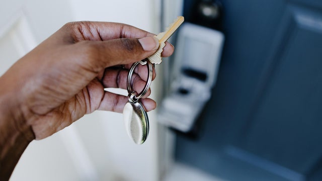 Real Estate Agent Accesses House Key From Lockbox Hanging on House's Front Door Handle 