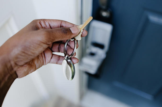 Real Estate Agent Accesses House Key From Lockbox Hanging on House's Front Door Handle 