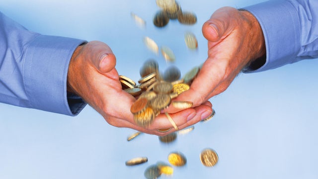 Gold coins falling through business man's hands 