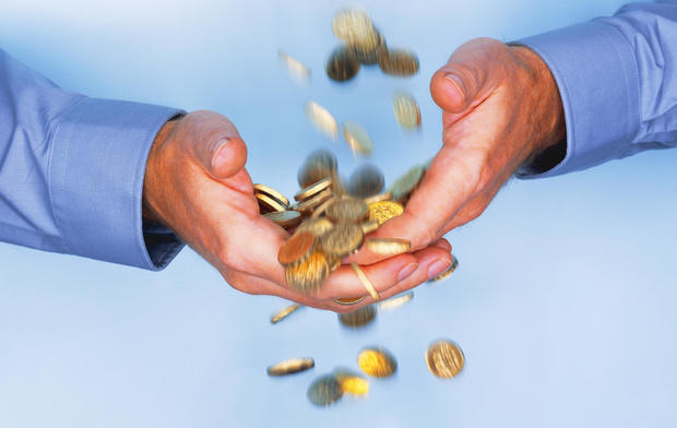 Gold coins falling through business man's hands 