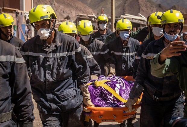 Moroccan rescuers carry a body out of the rubble in Talat N'Yacoub village of al-Haouz province in earthquake-hit Morocco on September 11, 2023.
