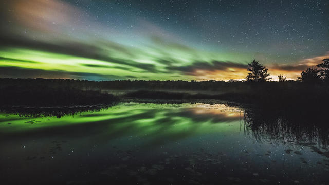 Reflection of aurora borealis on calm lake at night 