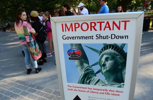 Tourists walk by a sign announcing that the Statue of Liberty is closed due to a government shutdown in New York on Oct. 1, 2013. 