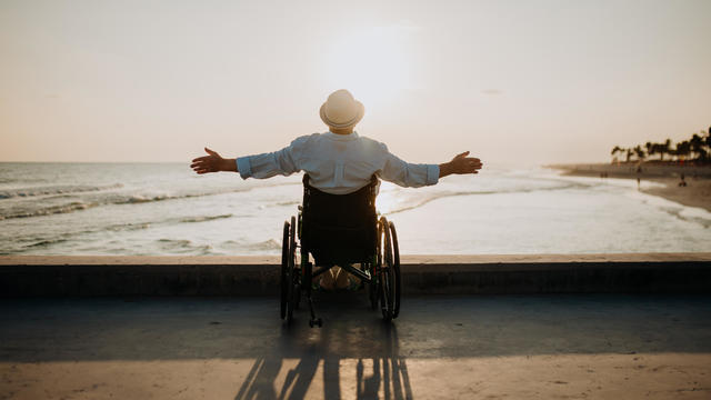 Rear view of man on wheelchair looking at sea. 
