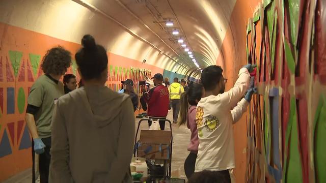 Dozens of people stand in the 191st Street tunnel painting the walls. 